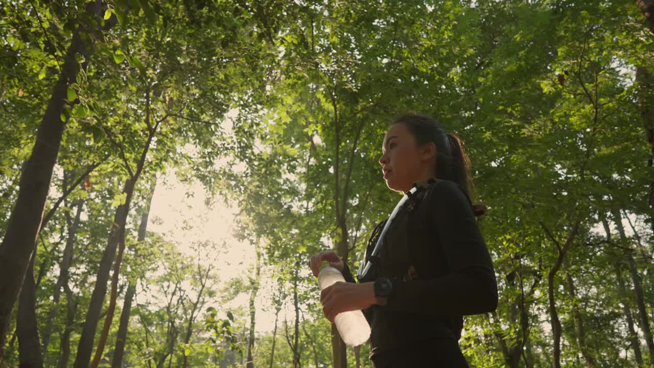 一个女人正穿过森林，手里拿着一瓶水视频下载