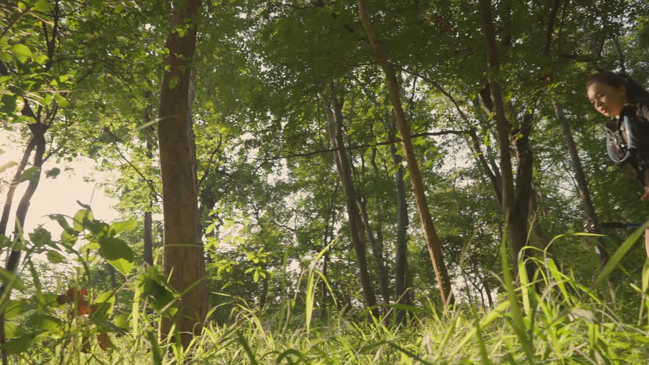 一个女人正穿过一片绿树成荫的森林视频下载