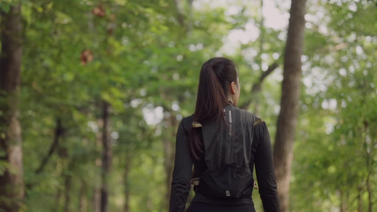 一个女人穿着黑色夹克走在森林里视频下载