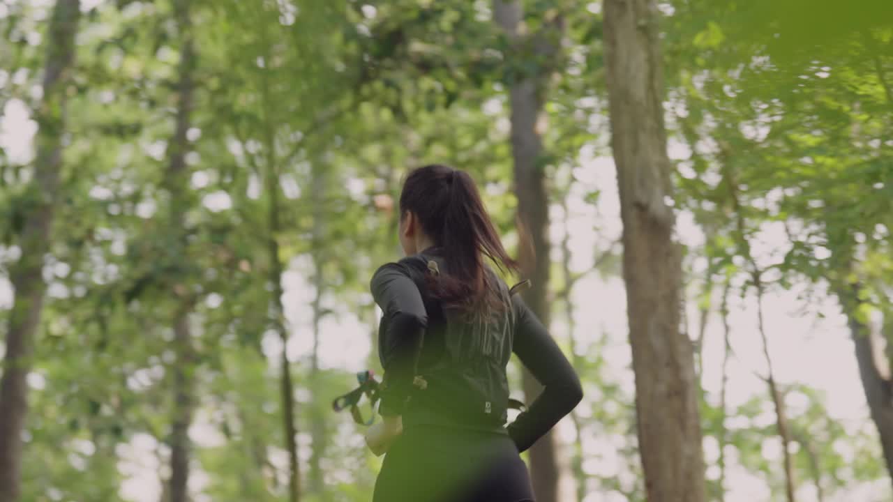一个女人手里拿着照相机正跑过森林视频下载