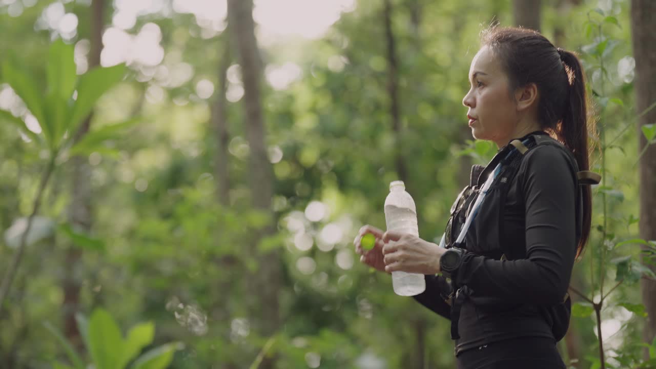 一个女人站在森林里，手里拿着一瓶水视频下载