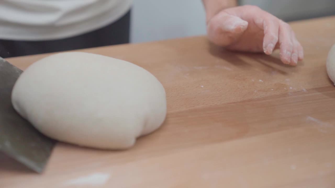 厨师用刮面板把面团揉成一条面包。面包师制作面包的手特写。视频素材