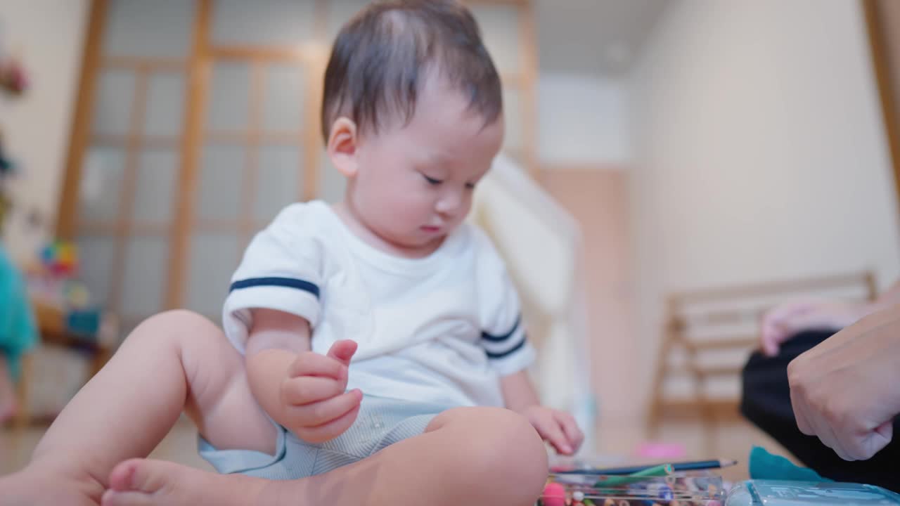 亚洲可爱的儿子和坐在地板上的妈妈一起玩粘土。视频素材