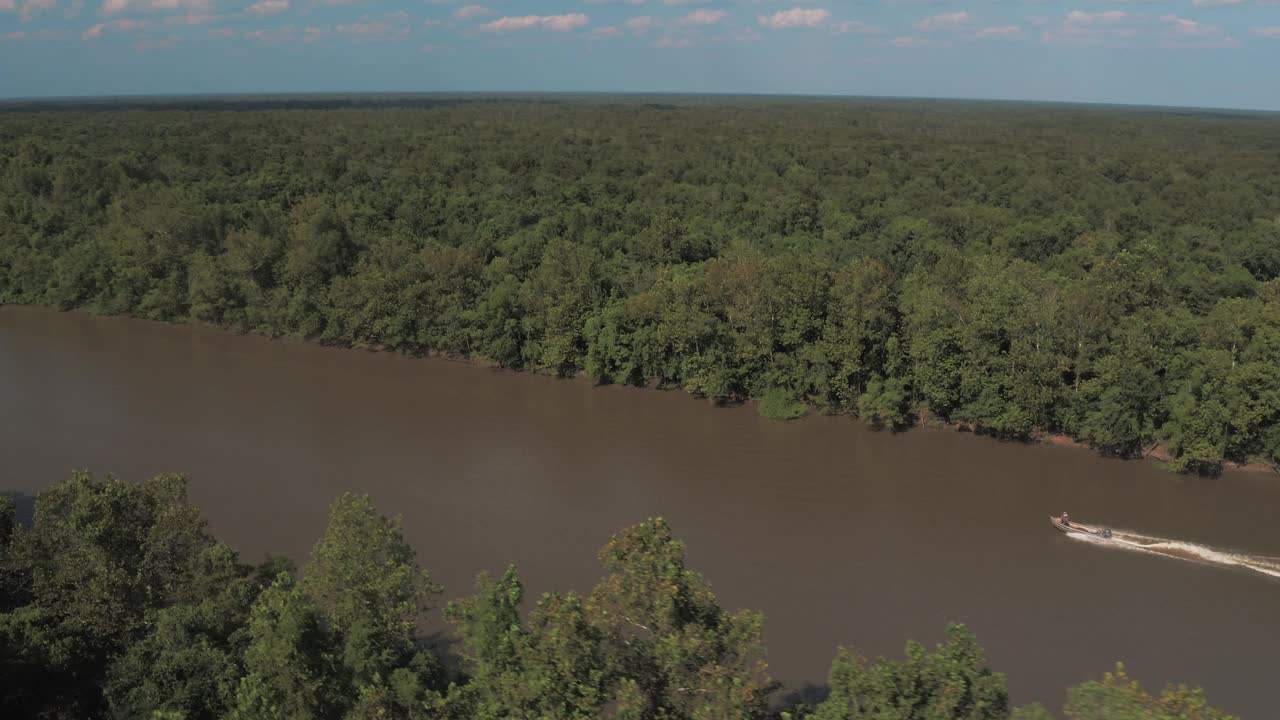 航拍向后拍摄的摩托艇在平静的绿色森林涟漪河上移动- Bayou Vista，德克萨斯州视频素材