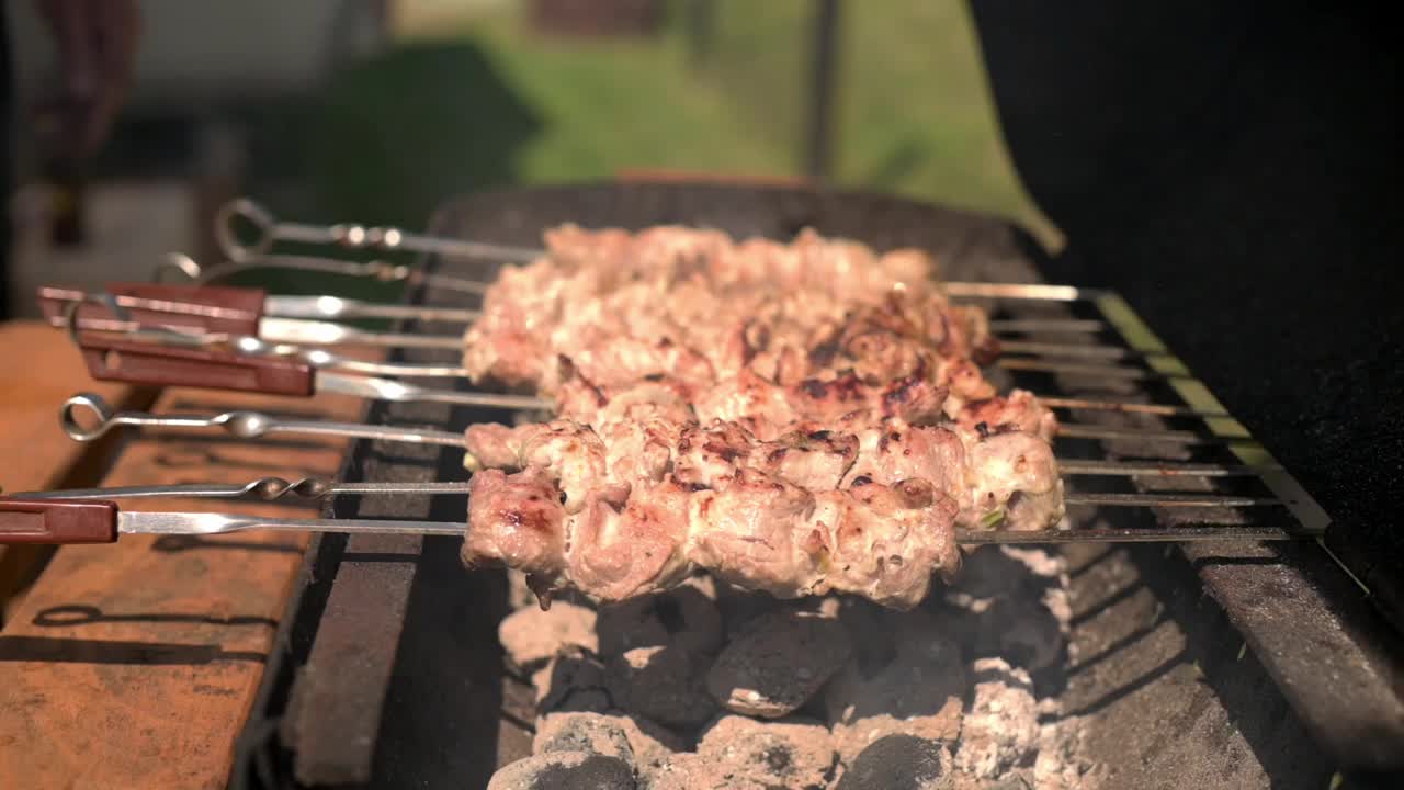 多汁的烤肉串在发光的木炭上烧烤，捕捉户外烹饪的精髓，把重点放在烤肉串上，模糊的背景强调烧烤的咝咝声和烟熏味视频素材