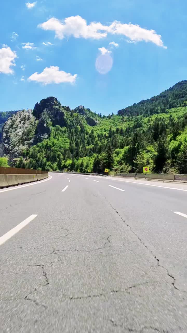 沉浸式驾驶沿着蜿蜒的山路行驶，周围是郁郁葱葱的绿色森林和令人叹为观止的景色视频素材