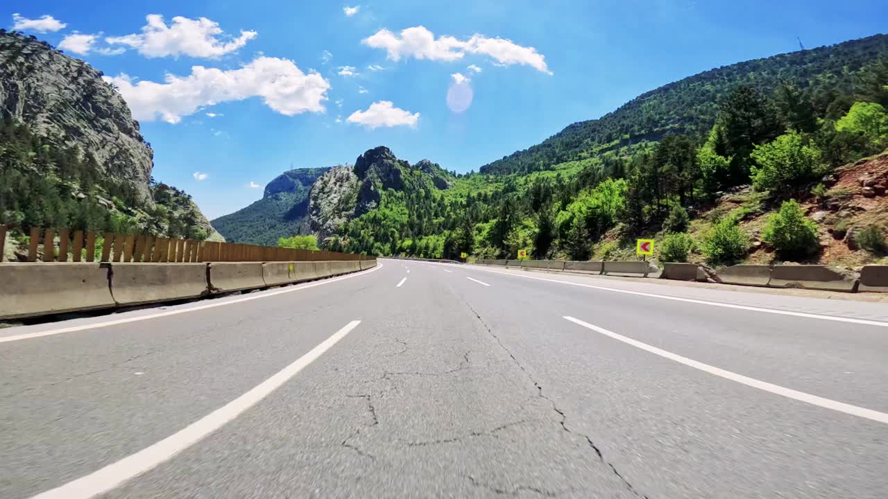 沉浸式驾驶沿着蜿蜒的山路行驶，周围是郁郁葱葱的绿色森林和令人叹为观止的景色视频素材