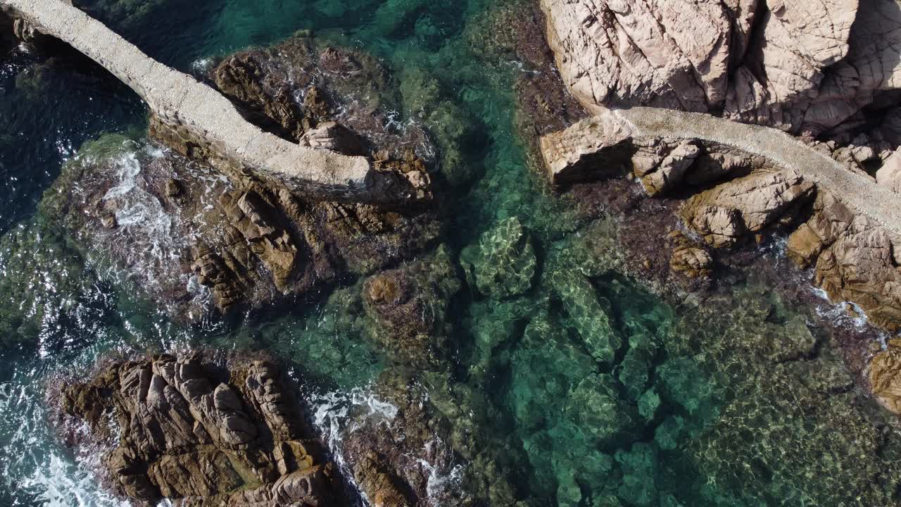 罗萨马岛礁石上破碎的走道鸟瞰图。清澈的水在Camí de Ronda，圣克里斯蒂娜德阿罗，布拉瓦海岸，加泰罗尼亚视频素材