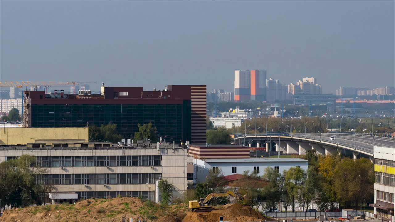 时间流逝。在炎热的夏天，在大城市背景的建筑工地上工作的大型挖掘机视频下载