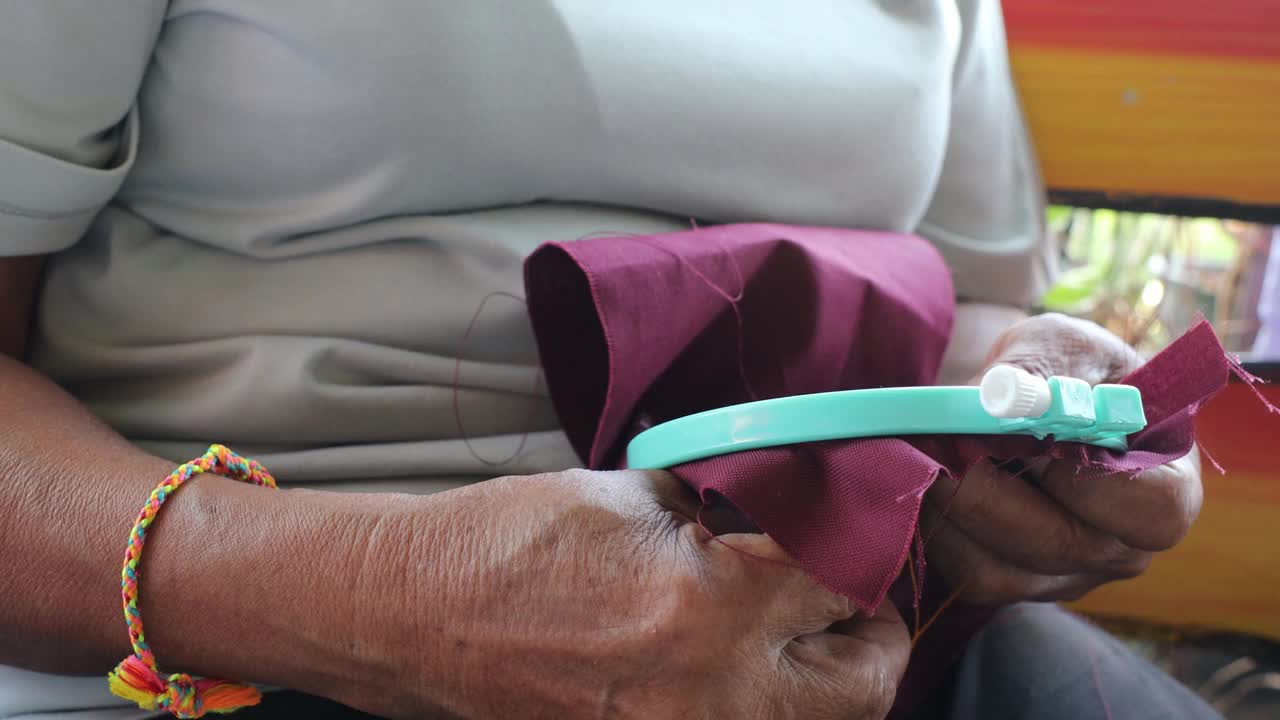 特写低角度，一位年长的泰国妇女的手熟练地刺绣字母设计。视频下载