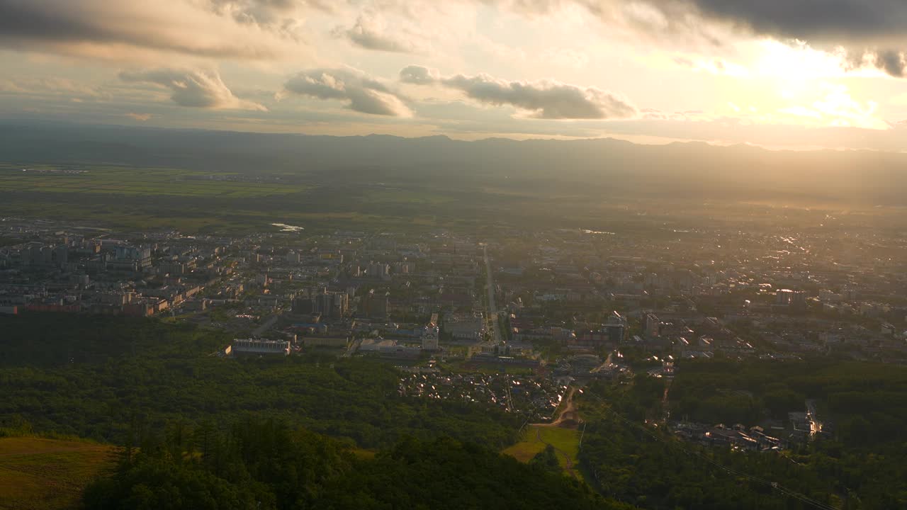 城市在绿色山谷的俯视图，太阳在地平线上。夹。美丽的风景，阳光明媚的绿色山谷与城镇在夏天的一天。明亮的阳光照耀着山谷和城镇视频素材