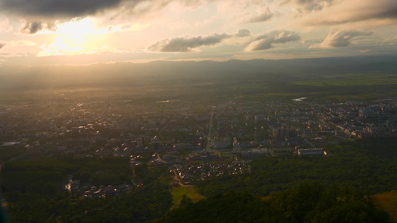 城市在绿色山谷的俯视图，太阳在地平线上。夹。美丽的风景，阳光明媚的绿色山谷与城镇在夏天的一天。明亮的阳光照耀着山谷和城镇视频素材