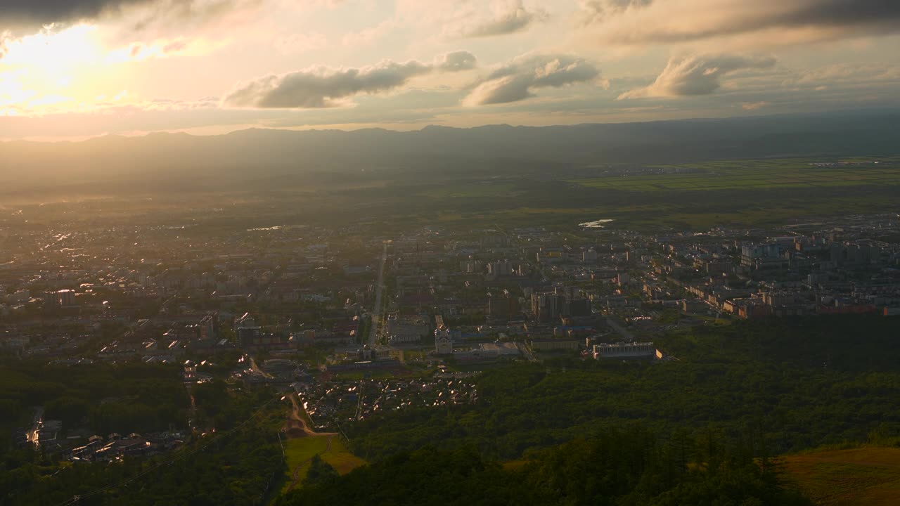 城市在绿色山谷的俯视图，太阳在地平线上。夹。美丽的风景，阳光明媚的绿色山谷与城镇在夏天的一天。明亮的阳光照耀着山谷和城镇视频素材