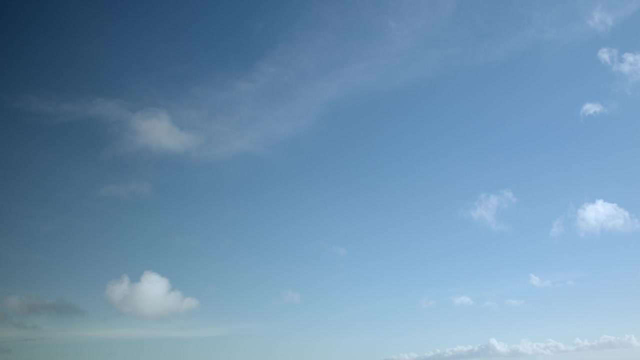 几朵白云在清澈的蓝天上平静地飞翔，加速延时视频，天空为背景。视频素材