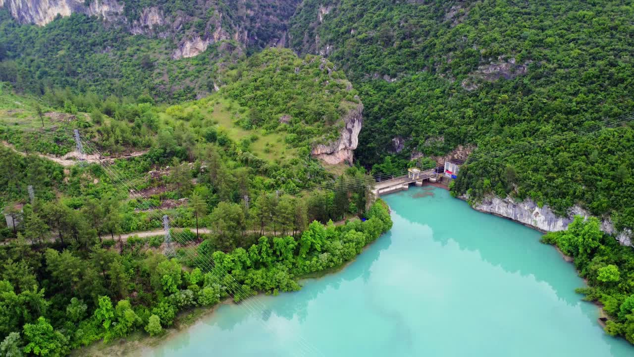 无人机看到的山绿松石湖和大坝。大坝横跨湖泊，突出水资源管理。绿松石湖映衬着周围的景观。大坝与湖泊的相互作用是显而易见的视频素材