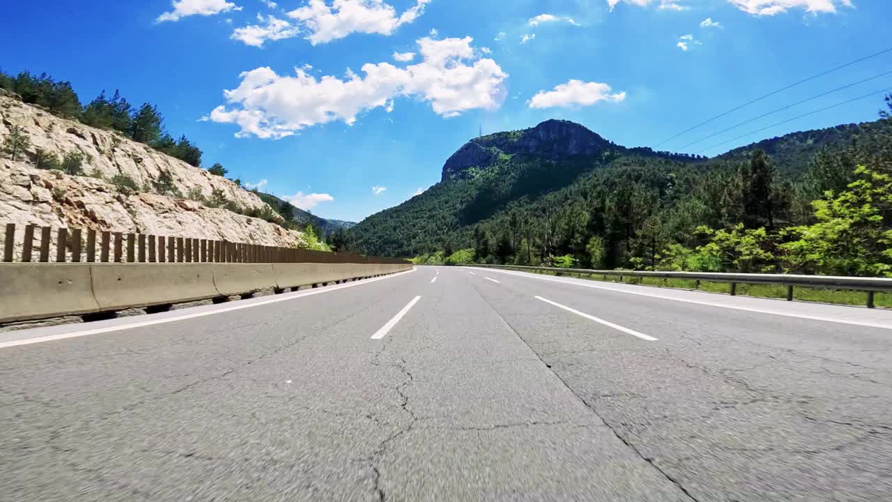 穿过蜿蜒的山路，远处有茂密的森林和高耸的山峰视频素材