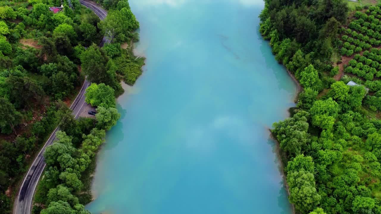 一条雄伟的蓝色河流蜿蜒穿过郁郁葱葱的绿树，令人惊叹的空中视角视频素材