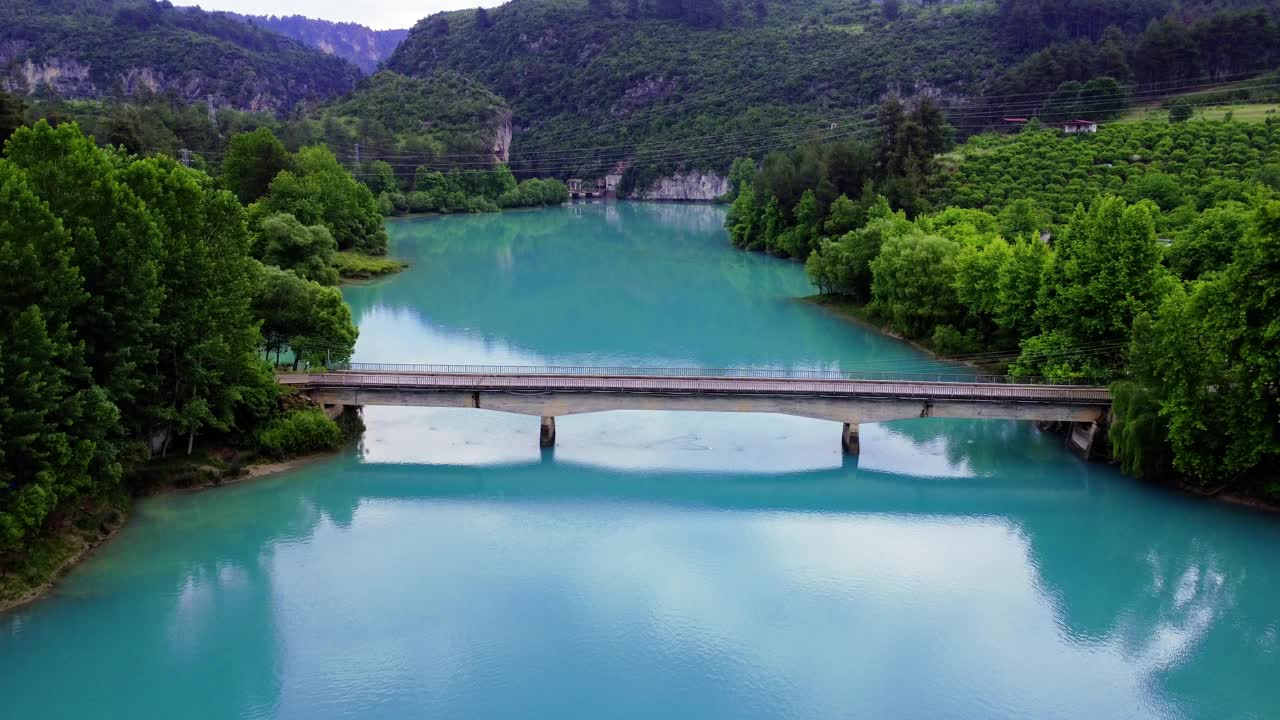 无人机捕捉山间湖上的桥梁，宁静的自然景色，桥梁连接海岸，建筑与自然无缝融合，宁静的山脉背景增强了桥梁景观视频素材