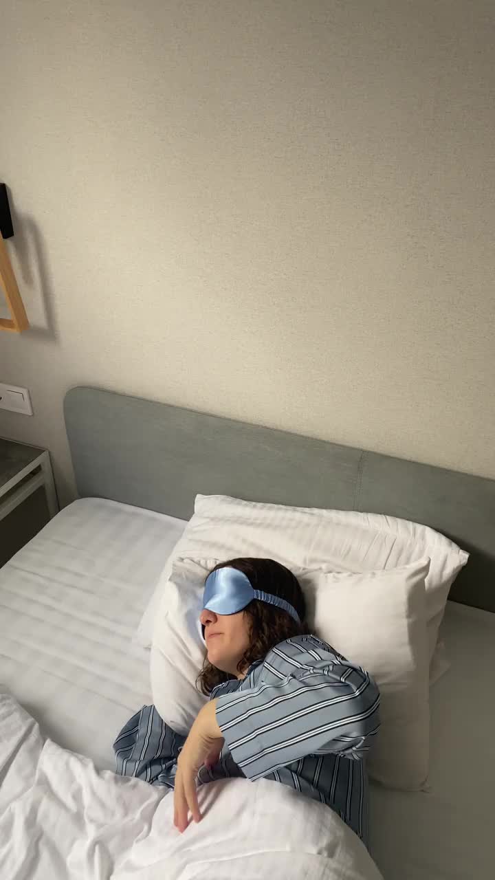 戴着睡眠面罩的年轻女子睡在床上，整理毯子视频素材