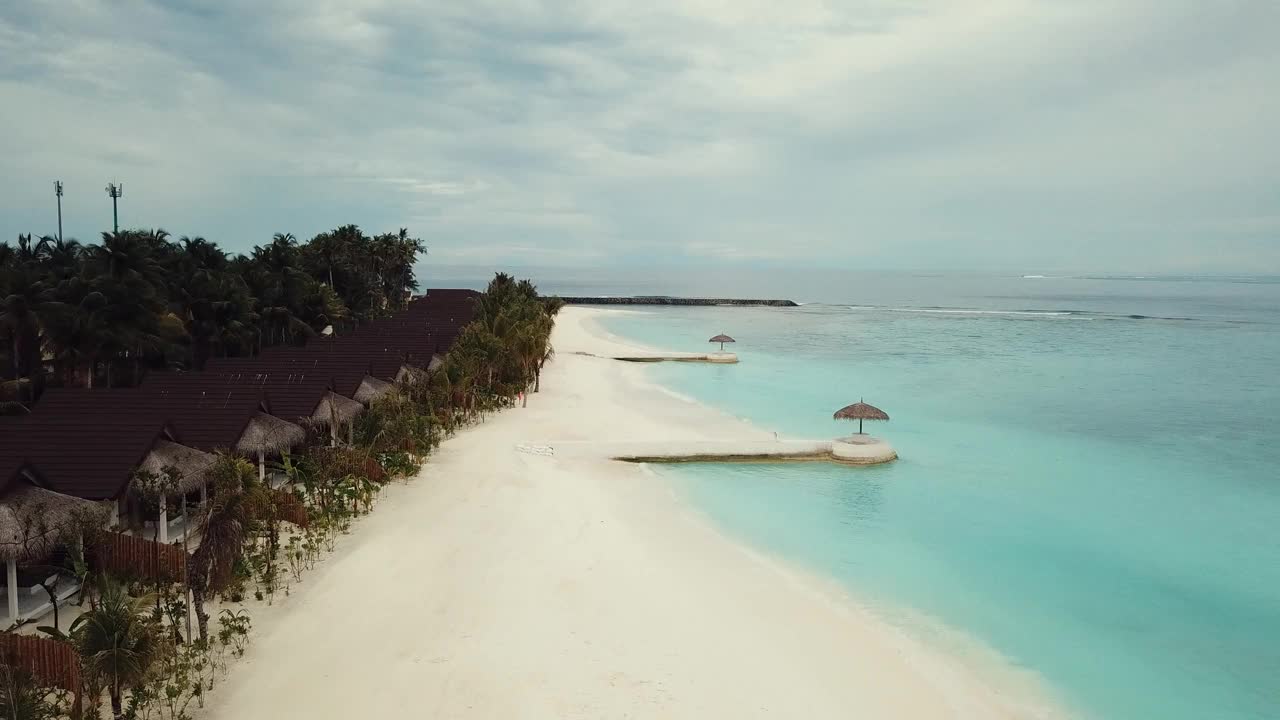 马尔代夫热带度假胜地的无人机视频，蓝色的泻湖，绿色的棕榈树，绿松石般的浅水，岛屿4K视频素材