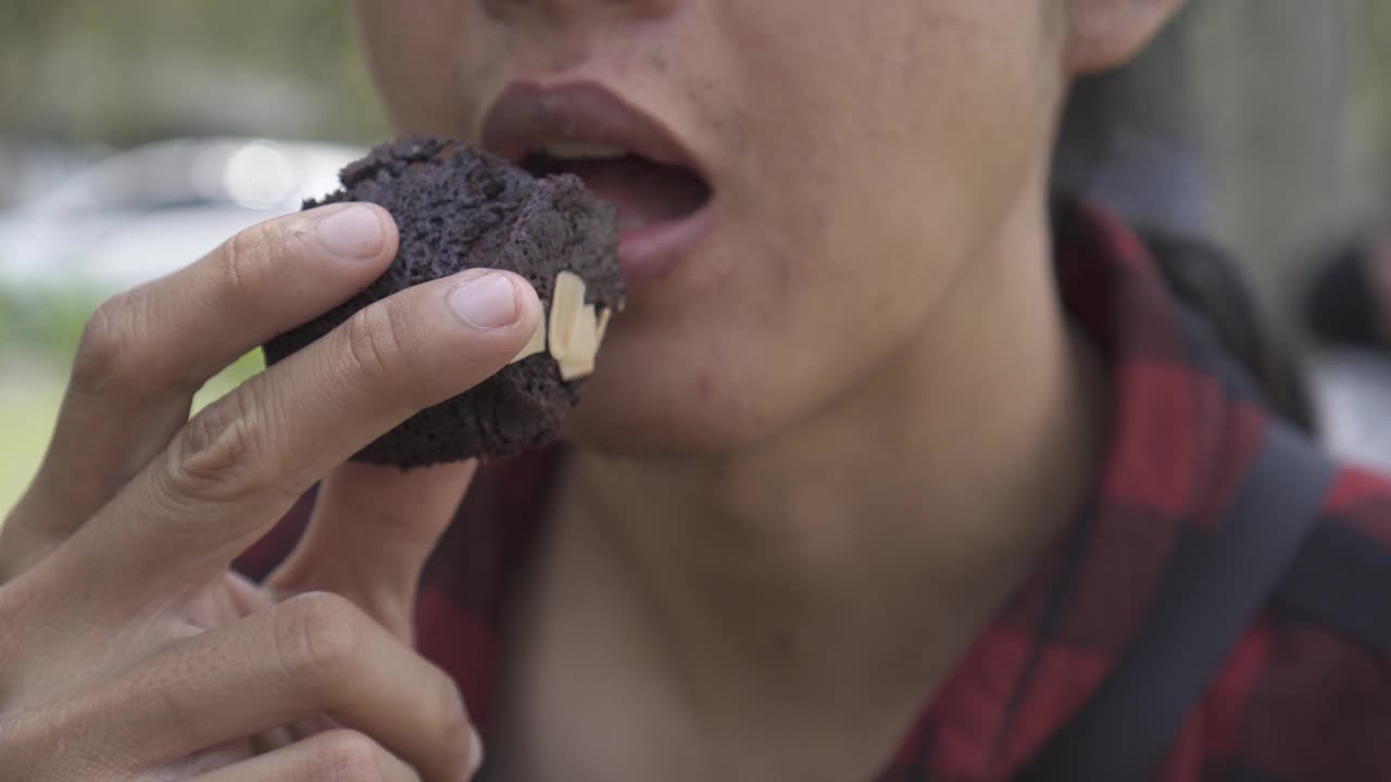 一个亚洲男人正在吃巧克力蛋糕上面撒着杏仁。不健康食品，减脂，减肥，不良饮食，糖尿病，胆固醇，胰岛素抵抗和代谢综合征的概念。视频素材