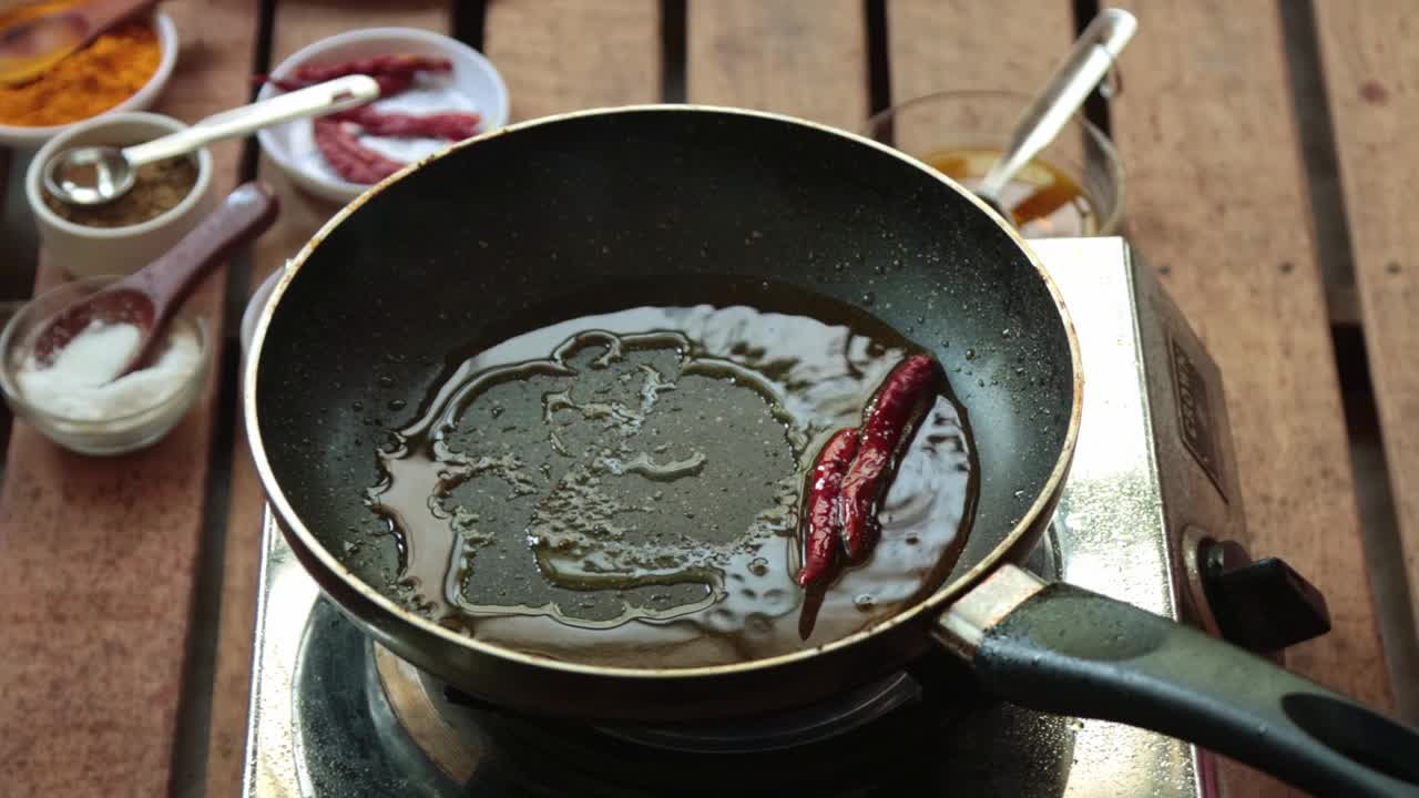 用芥末油炒小茴香籽和红辣椒。视频素材