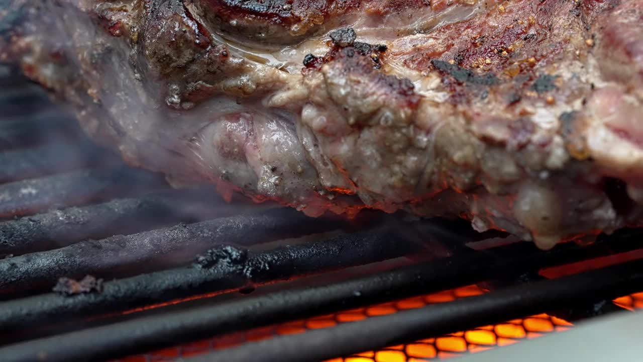 动物制品，最有可能是牛肉，在烤架上滋滋作响，散发出诱人的味道。在烹饪过程中使用了动物脂肪，在这个厨房里很快就成了一道美味的菜视频素材