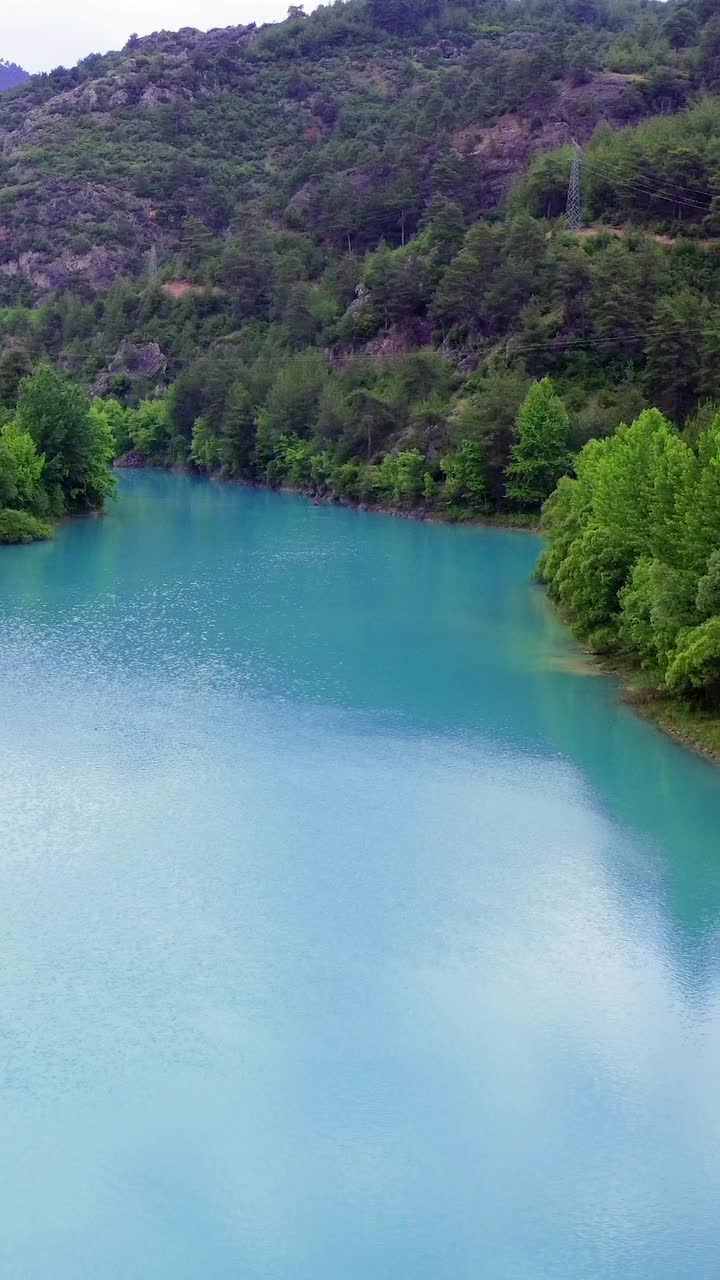 绿松石山湖的无人机视图显示宁静的景观。湖水映衬着周围的景观，形成了一幅完美的自然景观。视频捕捉到了湖泊和风景的完美和谐视频素材