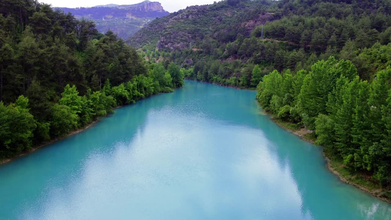 绿松石山湖的无人机视图显示宁静的景观。湖水映衬着周围的景观，形成了一幅完美的自然景观。视频捕捉到了湖泊和风景的完美和谐视频素材