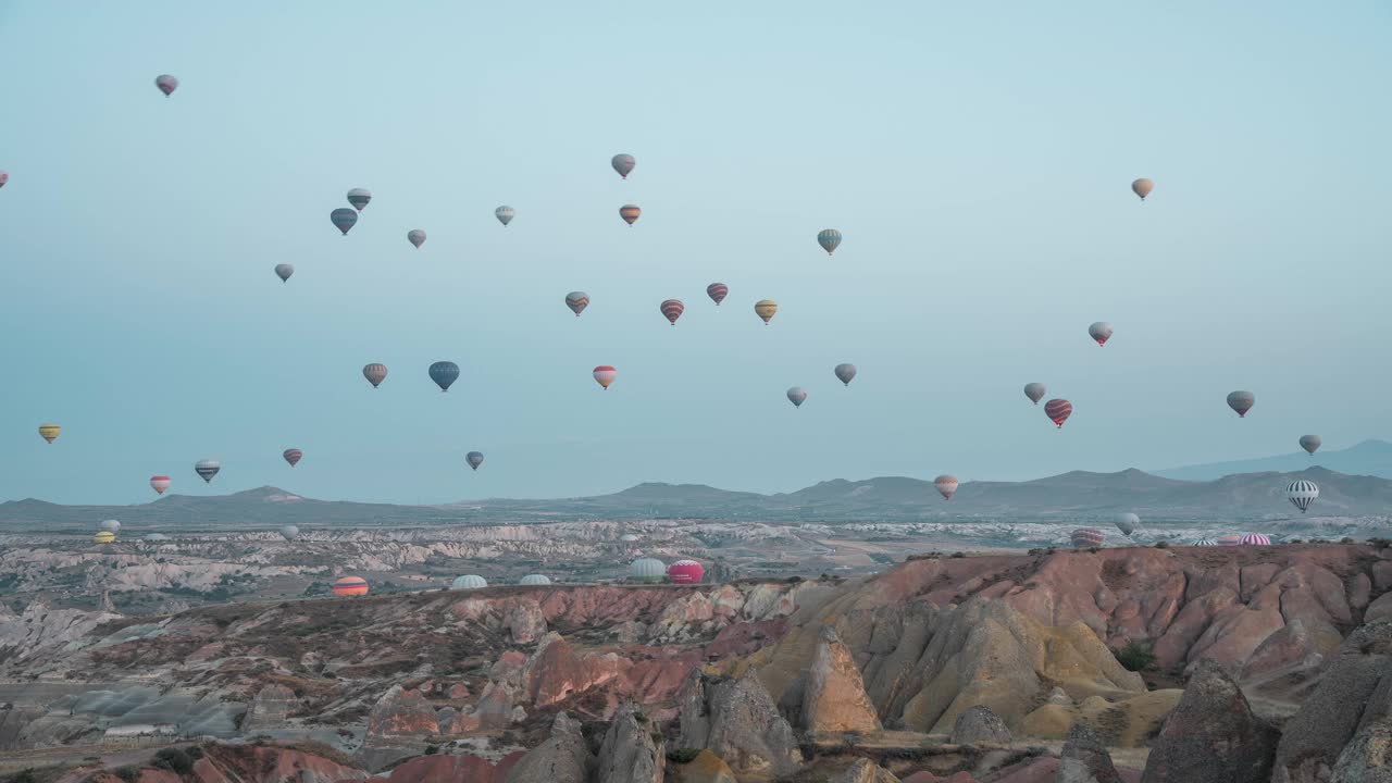 清晨，热气球飞越卡帕多西亚独特的风景，展现了美丽的黎明视频素材