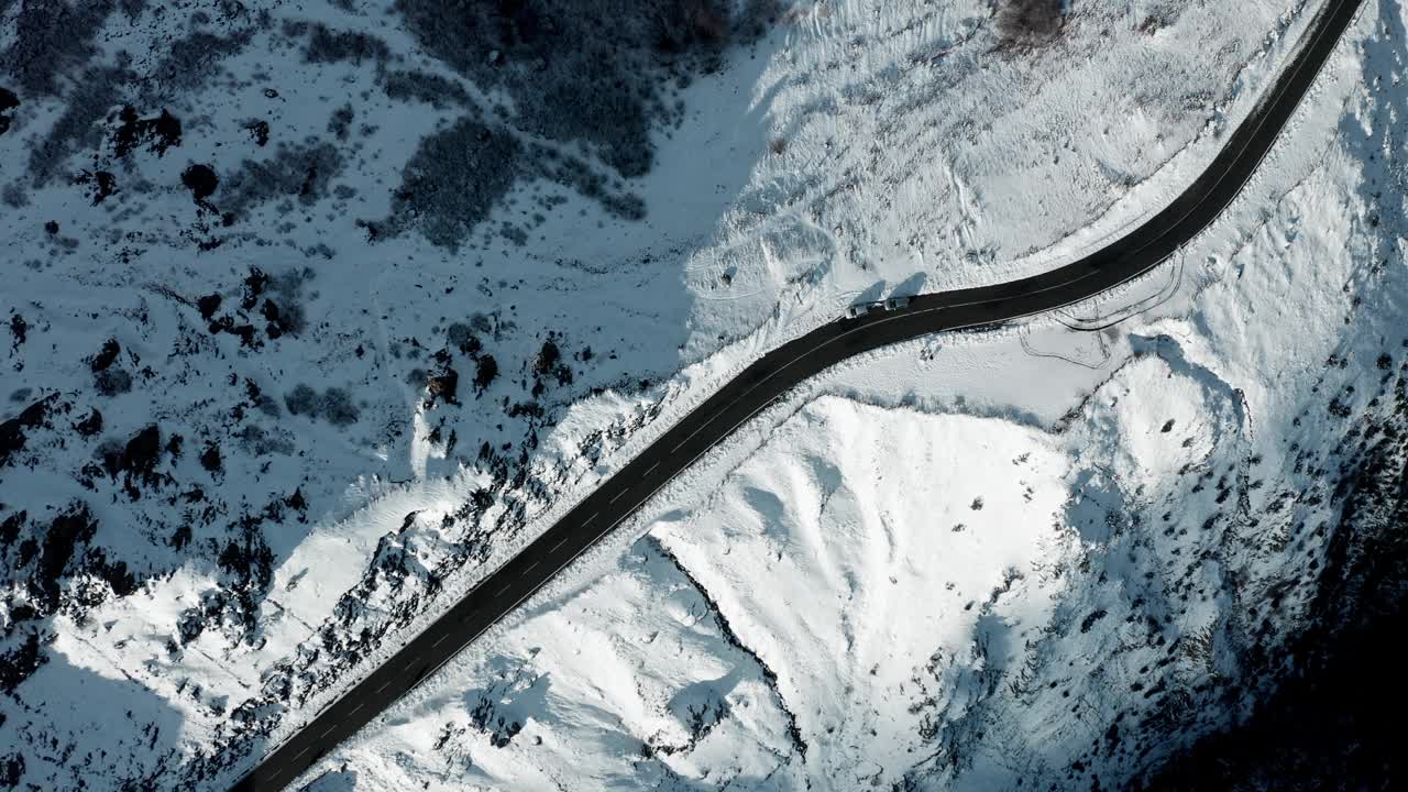 弯弯曲曲的道路穿过积雪覆盖的山间景观，鸟瞰视频素材