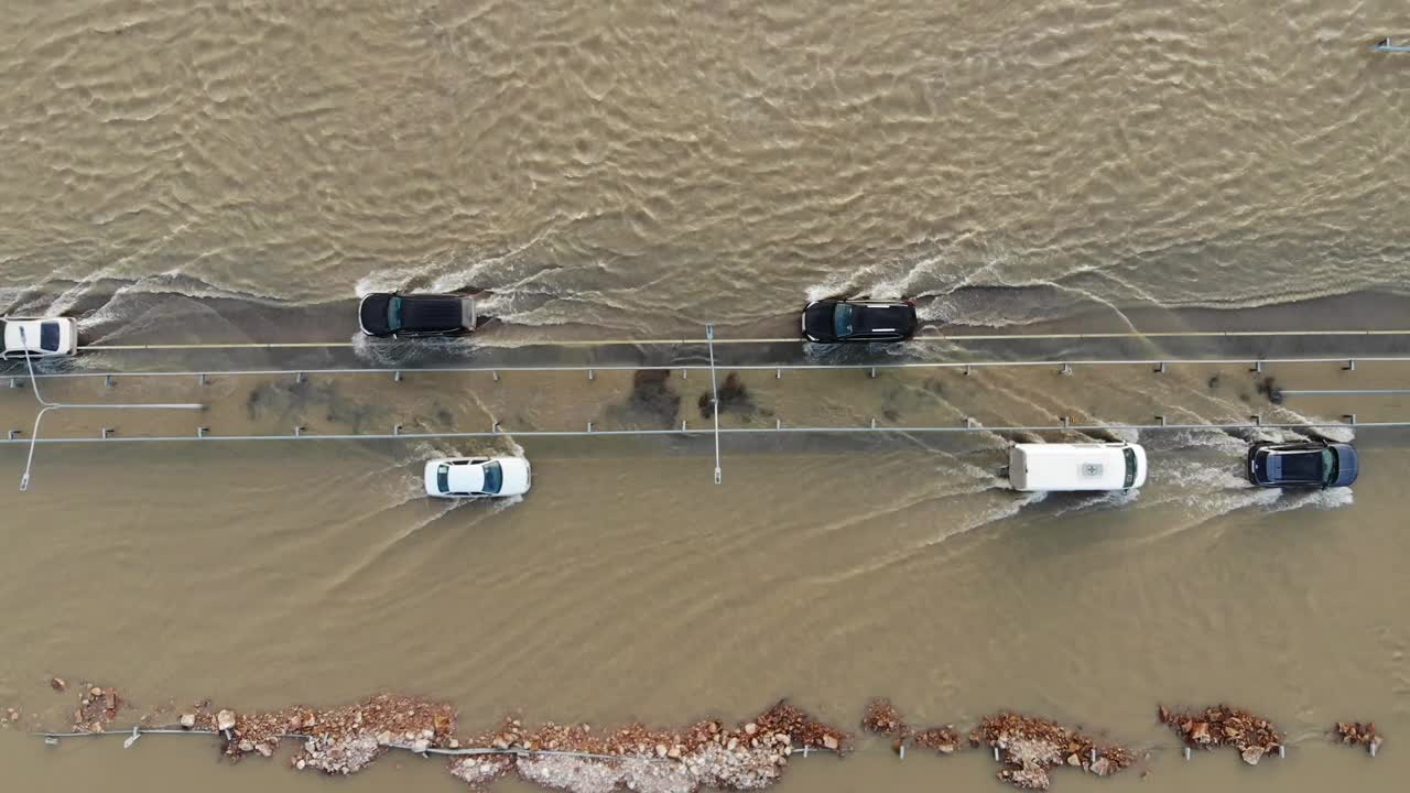 汽车和卡车行驶在被洪水淹没的高速公路上，在雨雪融化后的洪水中行驶视频下载