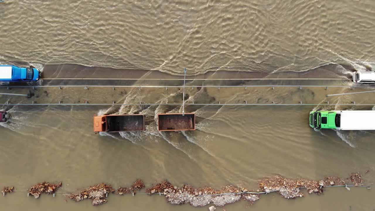 汽车和卡车行驶在被洪水淹没的高速公路上，在雨雪融化后的洪水中行驶视频下载