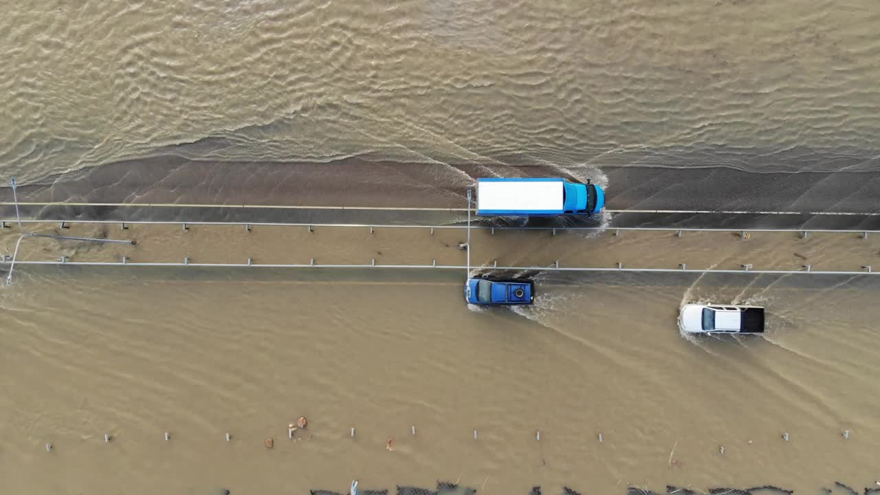 汽车和卡车行驶在被洪水淹没的高速公路上，在雨雪融化后的洪水中行驶视频素材