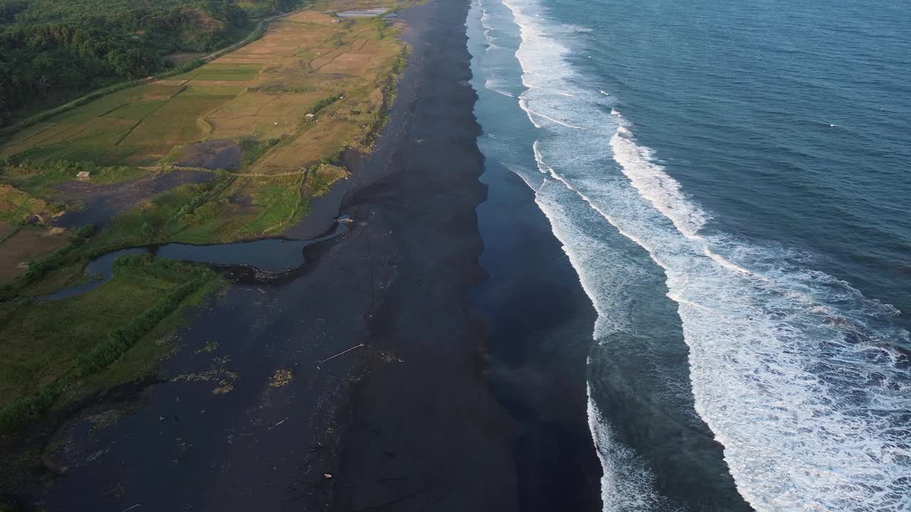 鸟瞰美丽的海滩景观，黑色的沙滩和海浪拍打着海岸线视频素材