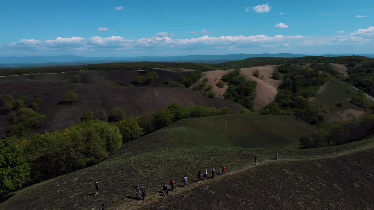 缓慢的无人机飞行在徒步旅行者穿越美丽的绿色山丘，平原和森林视频素材