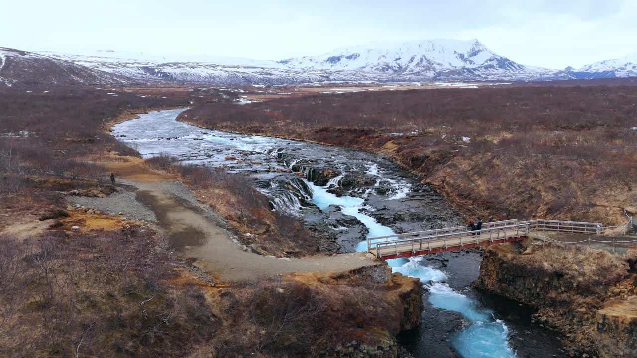 冰岛的布鲁尔福斯瀑布，背景是白雪覆盖的山脉，冬季场景，鸟瞰图视频素材