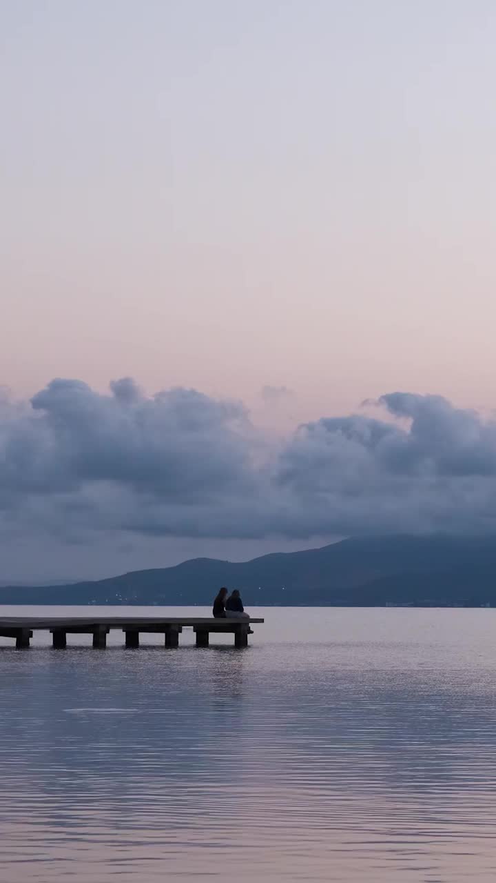 傍晚，在夏日夕阳的天空下，在海边的码头上放松的人们面目全非视频素材