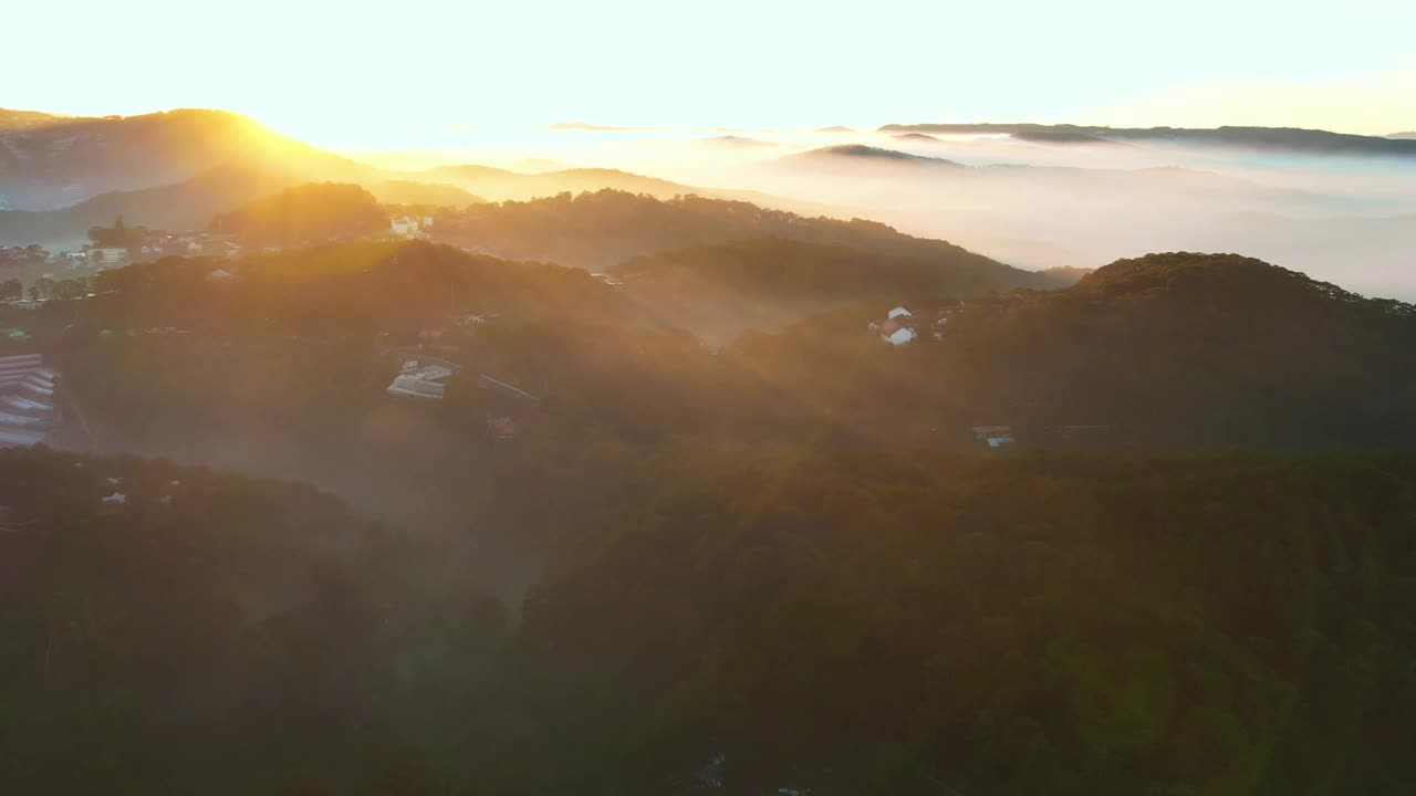 笼罩在薄雾中的达叻城，金色的日出照亮了葱郁的青山和错落的建筑，一派如画的宁静景象视频素材