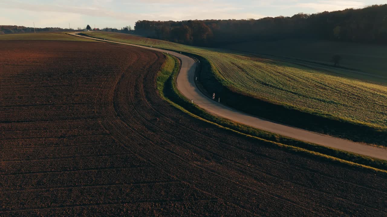 空中风景鸟瞰图蜿蜒的乡村道路沿着耕地在日落-完美的自然，旅游，和风景项目视频素材