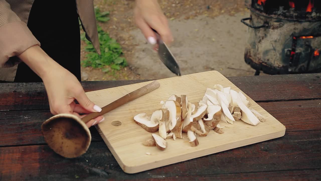 一个女人在明火旁用刀切香菇，家庭烹饪，自然的厨师视频素材