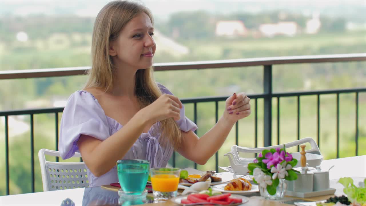 一名女子在阳光明媚的户外露台上享用早餐。视频素材