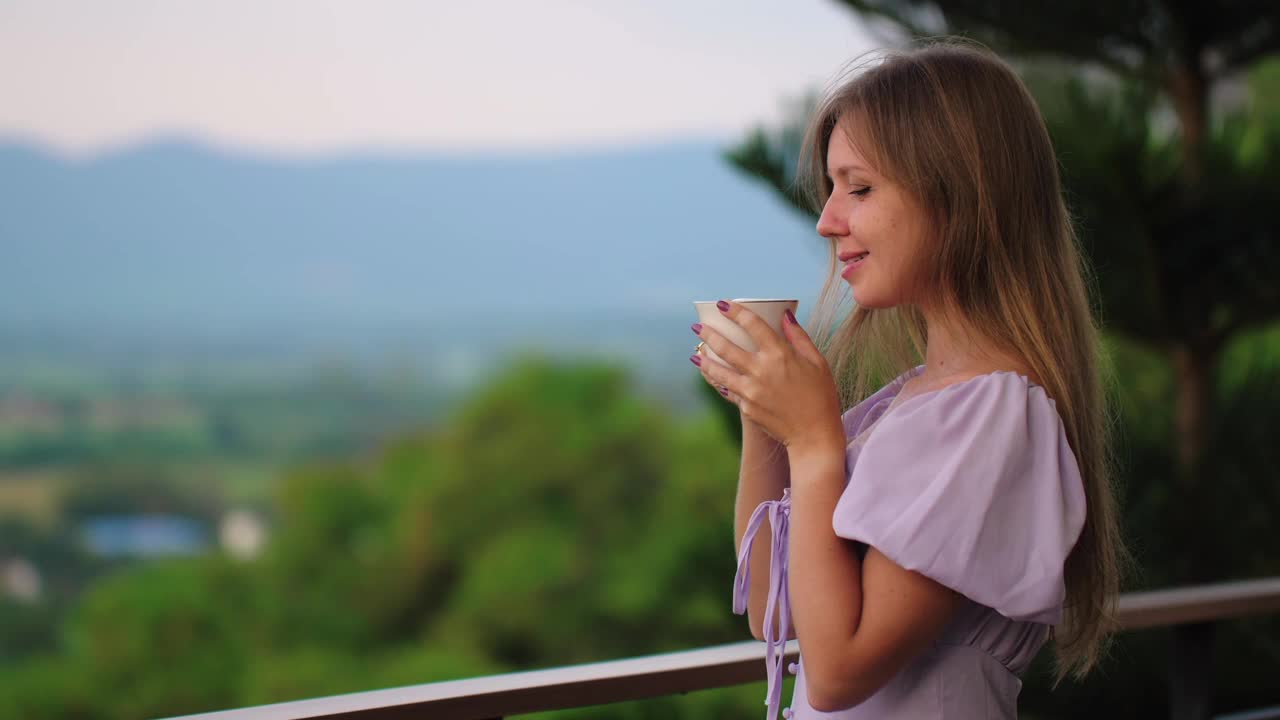 一名年轻女子在风景优美的阳台上喝咖啡视频素材