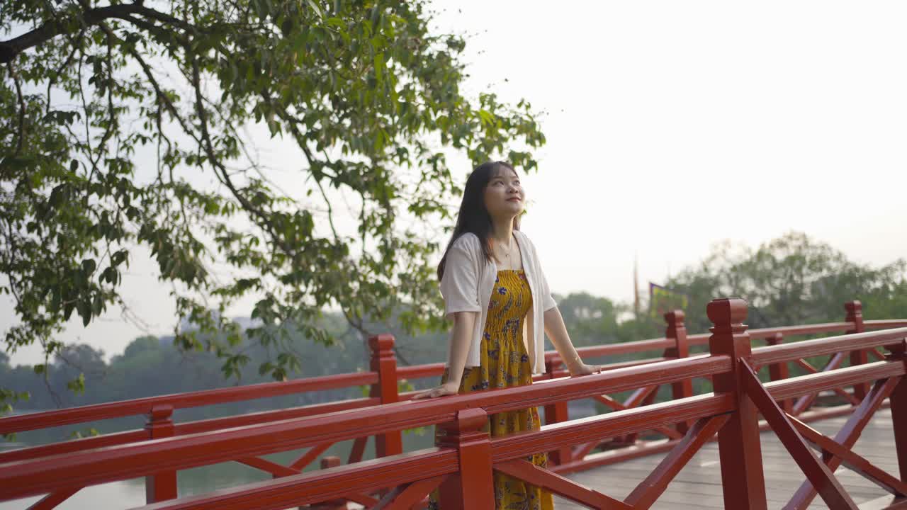 图为一名亚洲越南妇女在河内市中心还剑湖有树的公园里的红桥上旅行。越南的城市…视频素材