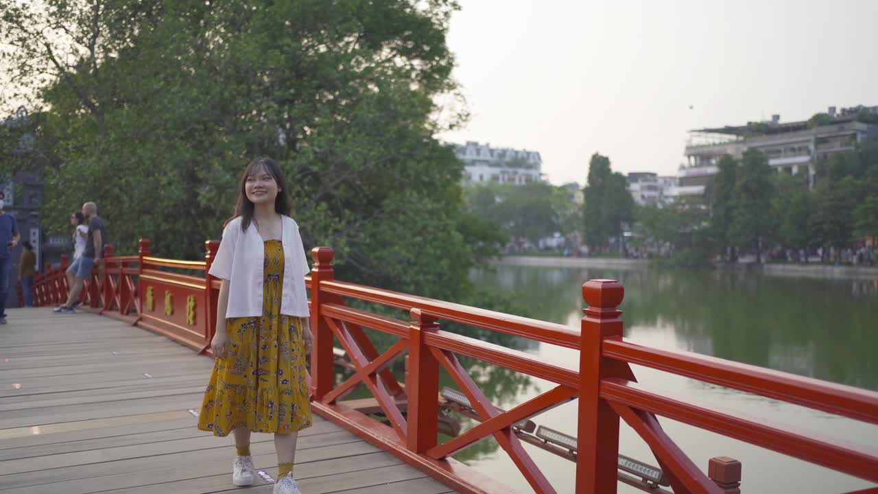 图为一名亚洲越南妇女在河内市中心还剑湖有树的公园里的红桥上旅行。越南的城市…视频素材