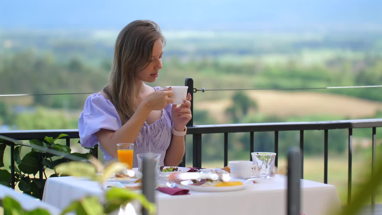 一名妇女在户外咖啡馆享用早餐，欣赏大自然的美景视频素材