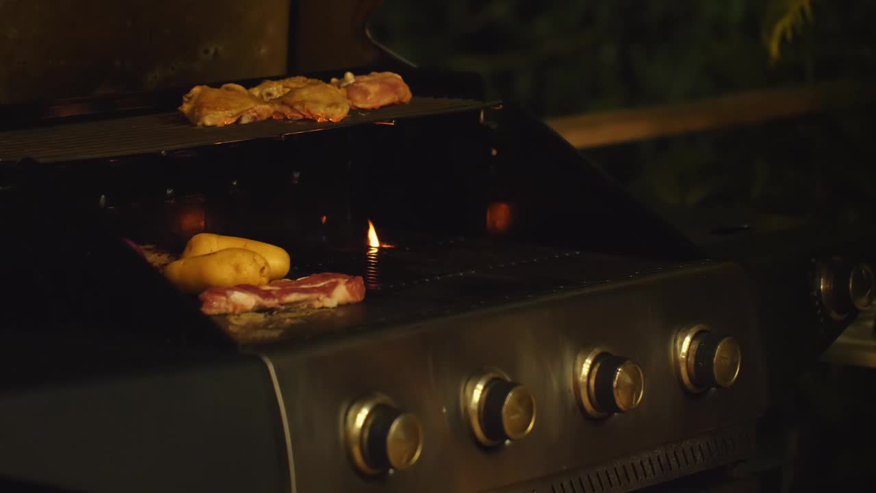 在温暖的夜晚，男人用烤肉架烤肉和蔬菜。视频素材