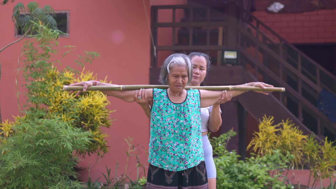 亚洲女性理疗师为一位老人做理疗，并在老人家中锻炼。治疗神经痛，关爱老年妇女健康。视频下载