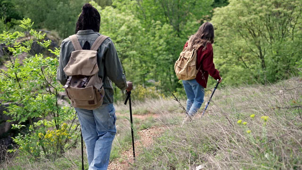 两个性格各异的朋友在山路上徒步旅行视频素材