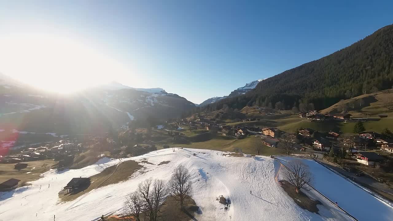 滑雪者在瑞士高山村庄的斜坡上。远处山峰上明亮的阳光融化了冬天的积雪，带来了夏天的户外活动，徒步旅行，登山和徒步旅行。视频素材